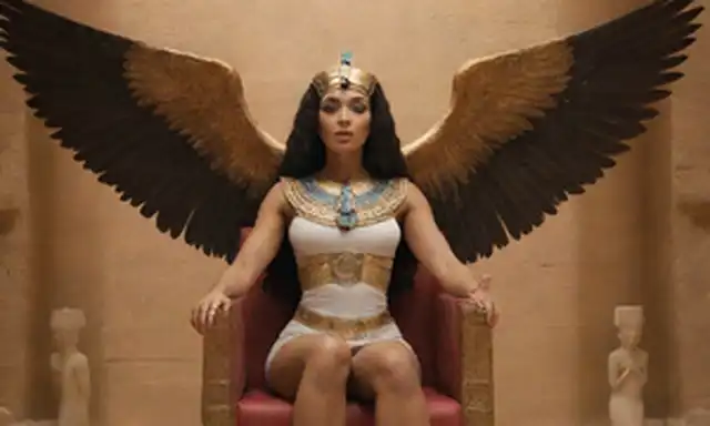 Diosa egipcia Isis con alas estremecidas, sentadas en un trono rodeado de cuerpos celestes, sosteniendo un ankh y un personal, con un brillo sutil emanando de su rostro, en medio de un telón de fondo de pirámides, estrellas y jeroglíficos, evocando el misticismo antiguo