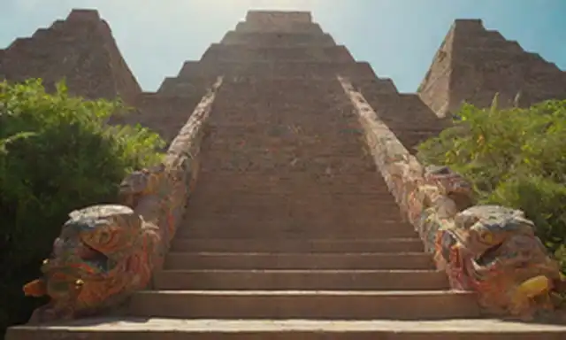 Emperador azteca Moctezuma II de pie en medio de una pirámide, rodeada de colores vibrantes y patrones intrincados, con un sol radiante en el fondo, una serpiente emplumada alrededor de él, una diosa mirando desde arriba, una figura guerrero en el lado, y exuberante vegetación cubriendo los pasos