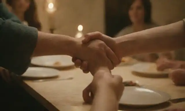 Manos sosteniendo manos, una comunidad reunida alrededor de una mesa, una comida compartida, un ambiente cálido y acogedor, iluminación suave, un sentido de unión, unidad, amor, alegría, espiritualidad, conversaciones profundas, momentos íntimos