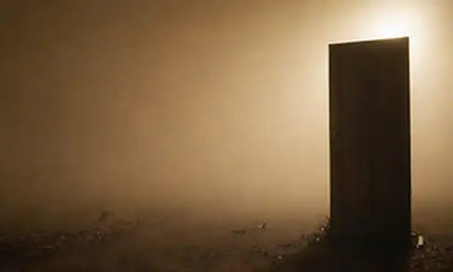 Una persona de pie en una encrucijada rodeada de niebla de incertidumbre, con dos caminos que conducen a una luz brillante y una sombra oscura; un pequeño pájaro volando lejos de un nido, dejando vacío; un espejo que refleja una cara familiar pero con una grieta sutil; una llave encerrada en una puerta oxidada