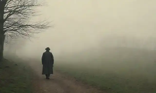 Paisaje europeo del siglo XVIII con colinas onduladas, árboles rústicos y un río de viento; una figura solitaria en un abrigo largo caminando hacia el horizonte, llevando una linterna; niebla de mal gusto que se levanta desde el suelo; colores suaves y mudos; juego sutil de luz y sombra