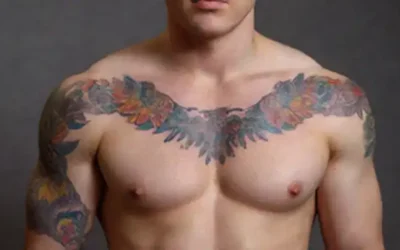 Una persona con un diseño de tatuaje audaz y colorido en su brazo o pecho; patrones intrincados y formas que se mezclan para crear una narrativa visual; simbolismo tejido a lo largo de todo